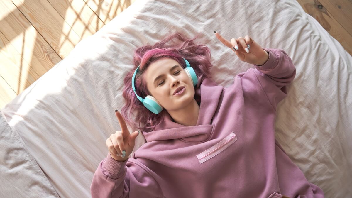 adolescente deitada na cama escuta musica - Turma - Inglês para adolescentes