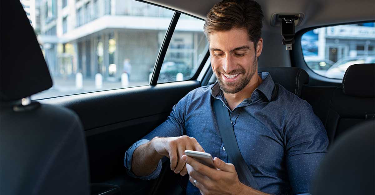 Pessoa com camiseta vermelha, segurando e usando um smartphone vermelho, em frente a uma parede azul acolchoada